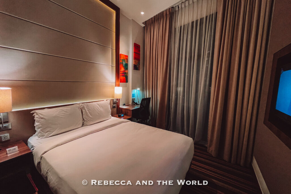 Modern hotel room at Holiday Inn Express Singapore Clarke Quay with a double bed, bedside lamps, desk, television and floor-to-ceiling curtains.
