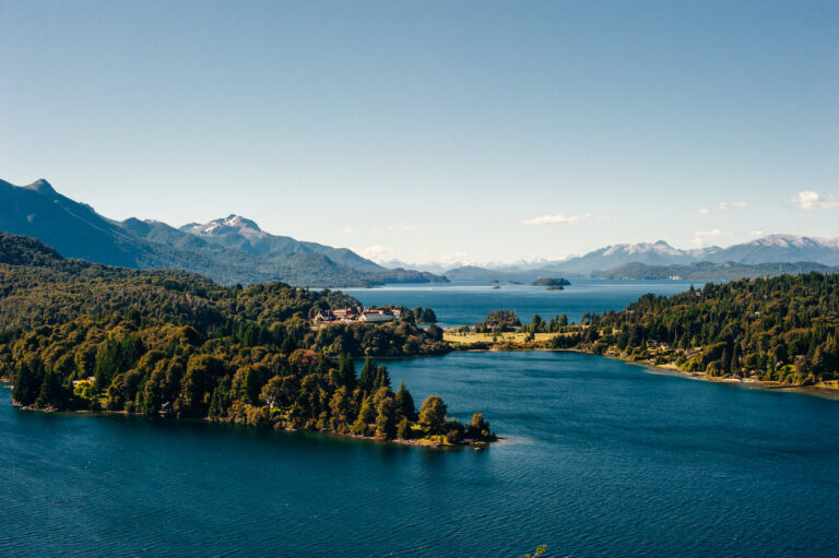 Panoramic view of Nahuel Huapi Lake near San Carlos de Bariloche, Argentina, showing forested islands, calm blue water, distant mountains, and a clear sky. Bariloche is one of the many places you can visit if you have 3 weeks in Argentina.