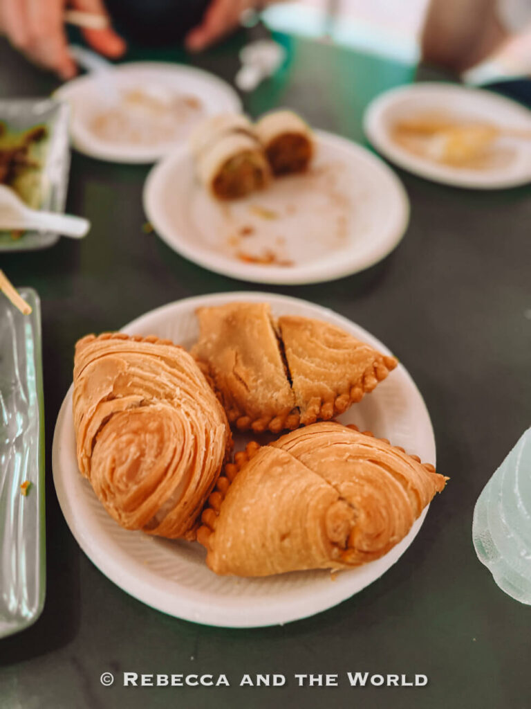 Three flaky Singapore curry puffs on a plate, a popular hawker snack