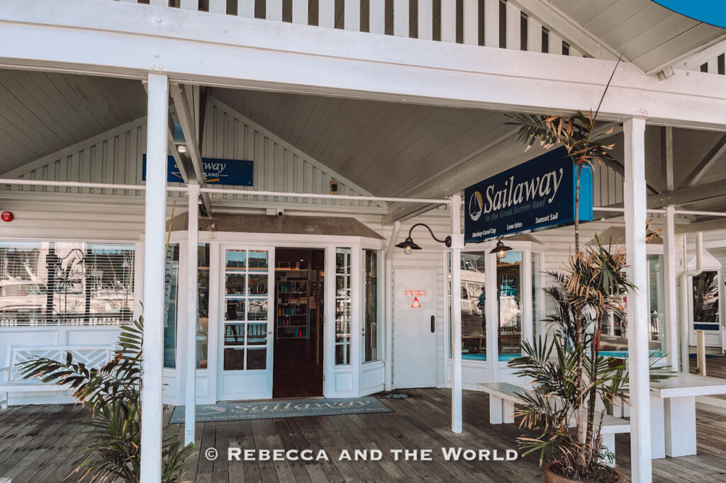 Exterior of the Sailaway Reef & Island Tours check-in office at Port Douglas marina, with signage listing its Mackay Coral Cay, Low Isles and sunset sail trips