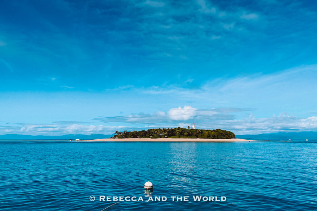 Low Isles from the water, showing its lighthouse and sandy beach fringed with palm trees, a popular Great Barrier Reef day trip stop from Port Douglas