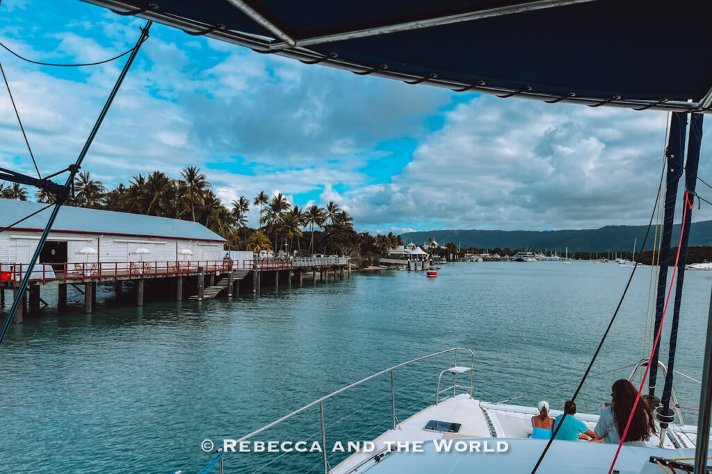 Sailing back into Port Douglas marina past the waterfront boardwalk and palm trees at the end of a Great Barrier Reef day trip