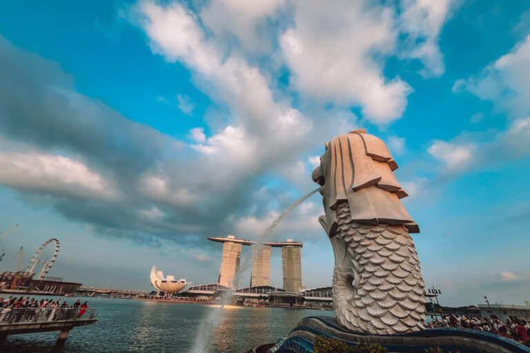 Close view of the Merlion spraying water into Marina Bay, with Marina Bay Sands and the lotus-shaped ArtScience Museum behind it.