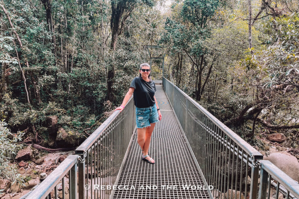 A woman (the author of this article) standing on the Rex Creek suspension bridge, a highlight of the Mossman Gorge walks on the way to the Rainforest Circuit Track